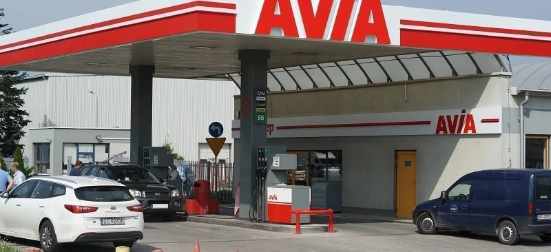 A family car parked at a filling station with the vehicle registration plate "5C92438" visible. The car has a gold bumper, automotive mirror and side-view mirror.