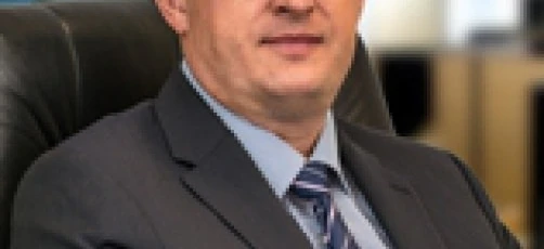 A businessman in formal wear sitting while wearing glasses and a dress shirt, representing professionalism and vision care.